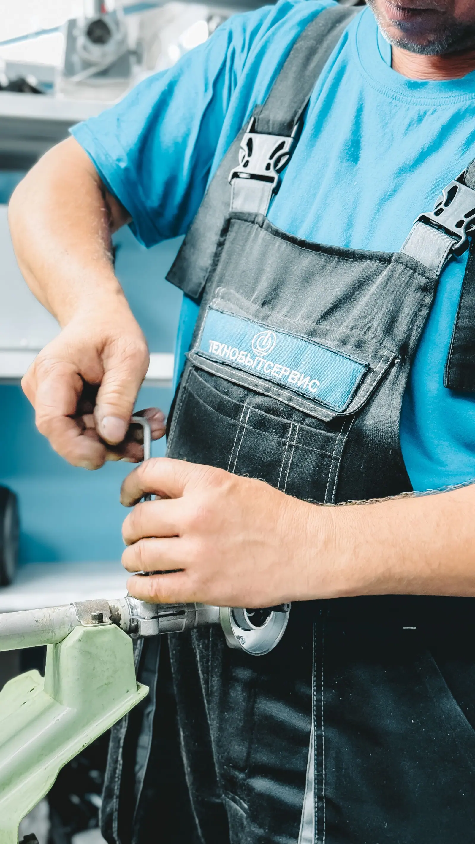 Chauffagiste en tenue bleue réparant une canalisation de chauffage à la clé à molette