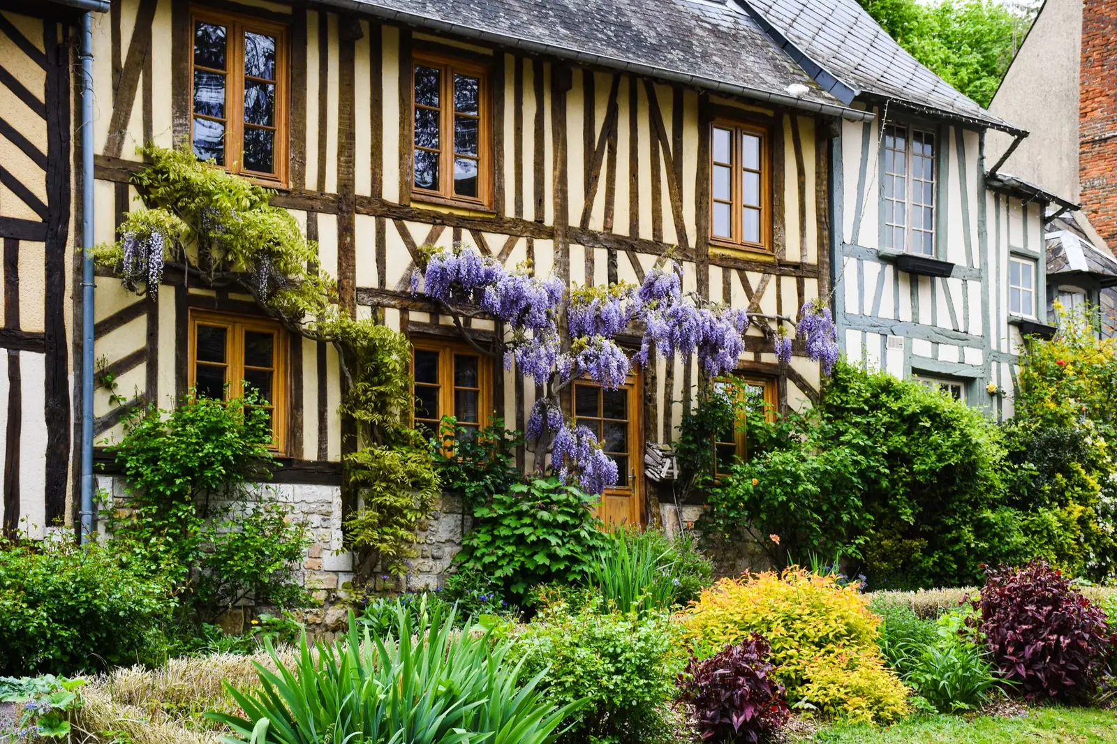 Maison normande à colombages avec jardin, représentative du bâti traditionnel de la région