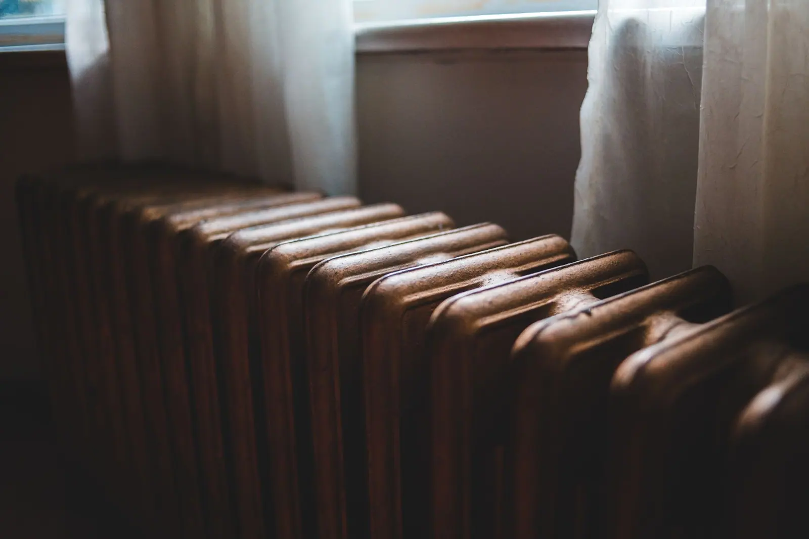 Radiateur en fonte ancien installé sous une fenêtre dans un logement d'époque